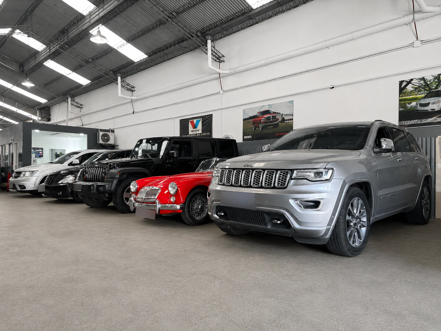 Jeep Grand Cherokee junto a un MG clásico rojo, un Jeep Wrangler, un Chrysler PT Cruiser y una Dodge Journey en el taller mecánico Lomayler en Villa Crespo, CABA