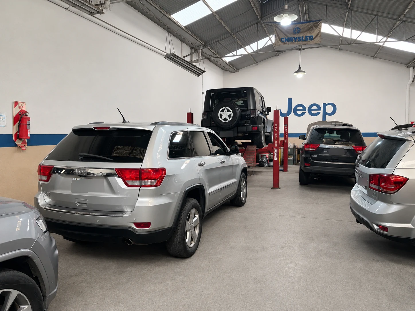 Jeep Wrangler sobre el elevador durante el service en el taller mecánico Lomayler, rodeado de Jeep Grand Cherokee, en Villa Crespo, CABA